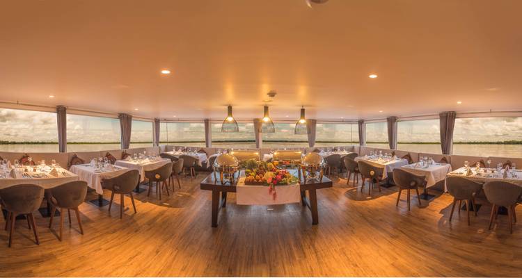 Geräumiger Panorama-Speisesaal auf einem Kreuzfahrtschiff, gedeckt für den Service mit Flussblick rundherum.
