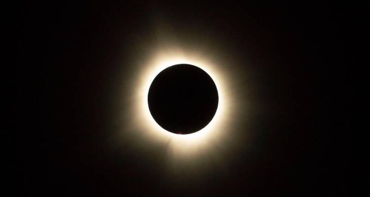 Un eclipse solar total que muestra el disco lunar oscuro rodeado por la corona resplandeciente.