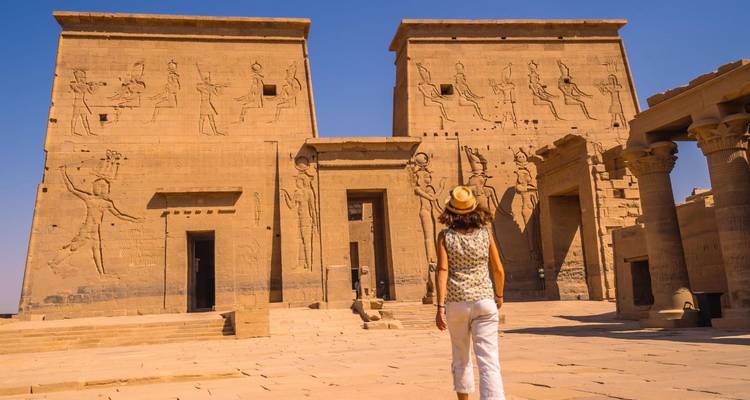Reisender nähert sich den antiken Steinpylonen des Philae-Tempels unter einem klaren blauen ägyptischen Himmel.