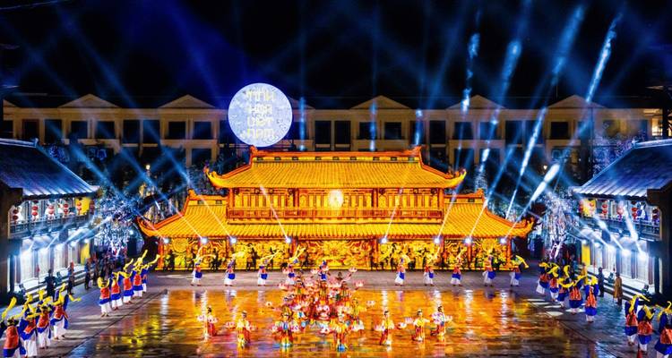 Grote verlichte toneelshow met dansers en muzikanten voor een traditionele paleisfaçade