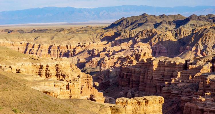 Weitläufiger Blick auf farbenfrohe, mehrschichtige Klippen und Schluchten des Charyn-Canyons im Sonnenlicht
