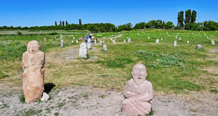 Besucher, die zwischen alten Steinbalbalen in offener Steppe unter blauem Himmel wandeln