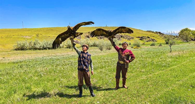 Kasachische Adlerjäger zeigen Steinadler auf grüner Hügellandschaft