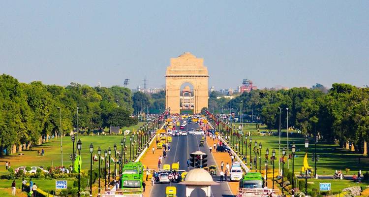 Larga avenida ceremonial que conduce a la Puerta de la India con tráfico y césped verde a ambos lados.