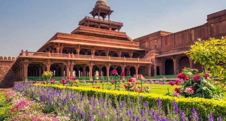 Pabellón del palacio de arenisca roja rodeado de arriates de flores coloridas dentro del complejo de Fatehpur Sikri.