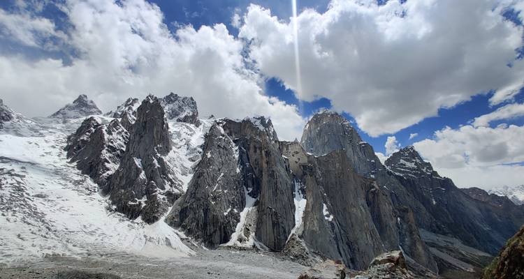 Des aiguilles de granit enneigées sous un ciel lumineux avec des formations nuageuses spectaculaires.