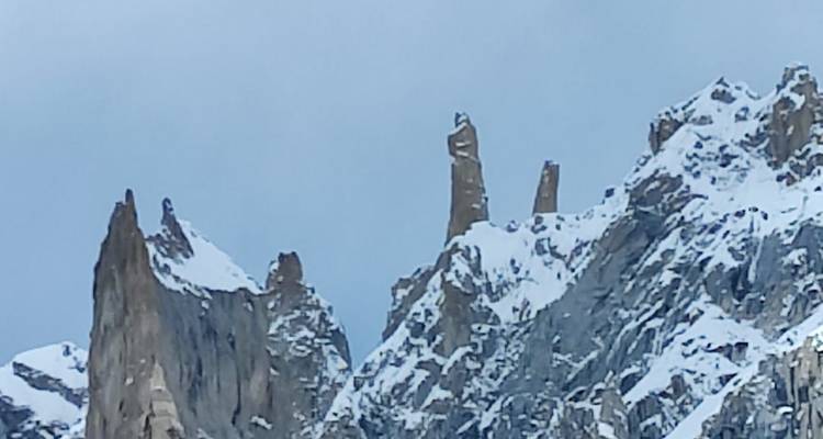 Vue rapprochée d'aiguilles rocheuses enneigées fines comme des aiguilles contre un ciel gris.