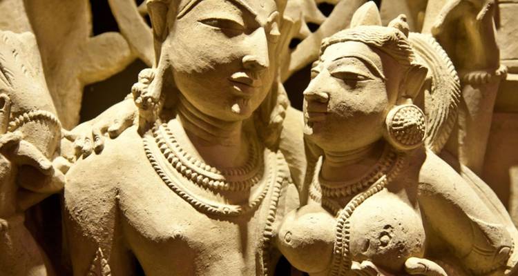 Detailliertes erotisches Steinskulptur-Panel aus den Khajuraho-Tempeln mit mythologischen Figuren.