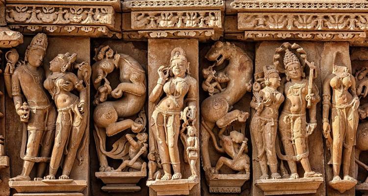 Komplizierter Steinfries mit mehreren stehenden Gottheiten und Tieren in Khajuraho.