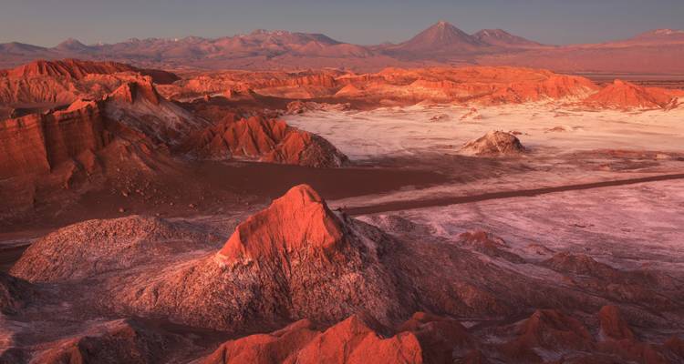 Dramatische rote Felsformationen des Valle de la Luna in der Abenddämmerung mit Andengipfeln in der Ferne