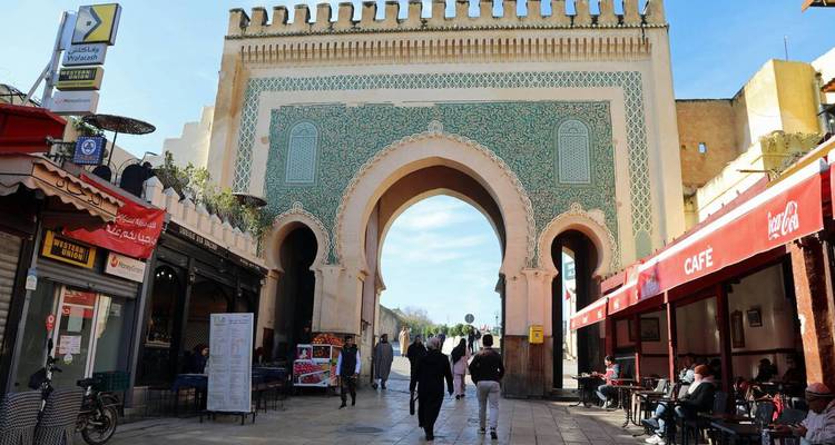 La porte Bab Bou Jeloud aux tuiles bleues à Fès avec des piétons marchant sous sa grande arche