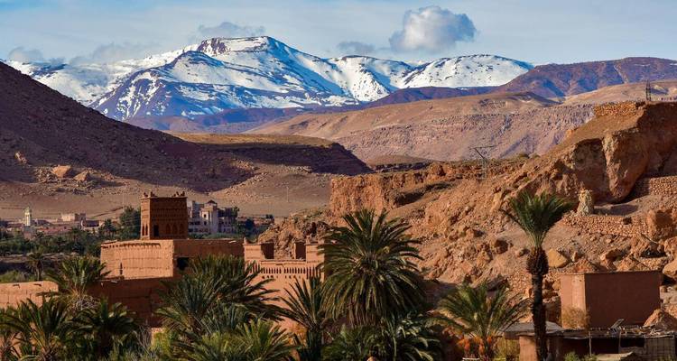 Montagnes de l'Atlas enneigées se dressant derrière une oasis de palmiers et des kasbahs en adobe près de Ouarzazate