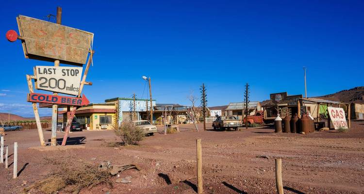 Avant-poste désertique dans le style d'un plateau de cinéma rétro avec de vieilles voitures, des pompes à essence et un panneau indiquant « Dernier arrêt 200 miles »