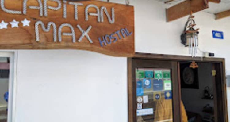 Grainy exterior photo of a hostel entrance with wooden sign reading 'Capitan Max'.
