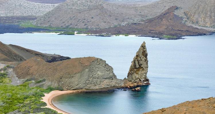 La icónica Roca Pináculo elevándose abruptamente desde las aguas cristalinas de la Isla Bartolomé con una playa en forma de media luna debajo.