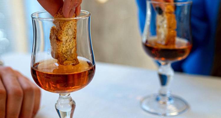 Biscuit cantucci trempé dans du vin de dessert ambré servi dans de petits verres.