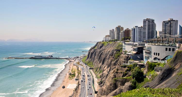Clifftop skyline of Lima overlooking a coastal highway, beaches and blue Pacific waves.