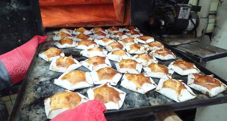 Tray of golden-brown pastries baking inside a traditional oven.