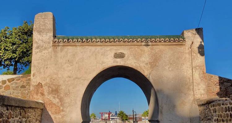 Simple arche de porte en pierre menant à une médina marocaine historique.