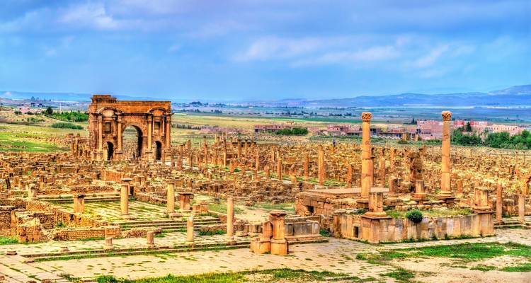 Vastes ruines romaines de Timgad avec arc et colonnes éparses sur un haut plateau