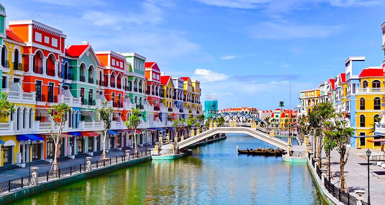 Farbenfrohe europäische Kanalstadt mit regenbogenfarbenen Reihenhäusern und gewölbter Fußgängerbrücke auf der Insel Phu Quoc.
