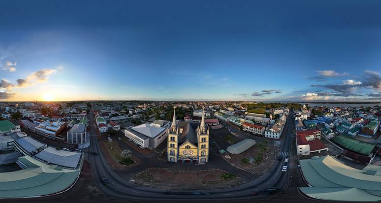 Vista aérea de 360 grados del amanecer sobre una ciudad ribereña con una gran catedral dominando el centro.