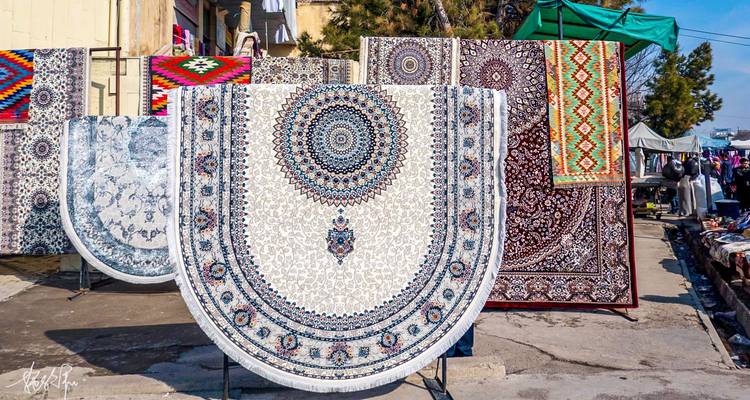 Mercado de alfombras al aire libre con alfombras de patrones intrincados colgando bajo la brillante luz del sol.