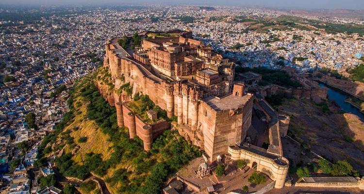 Dramatische Luftaufnahme der massiven Festung Mehrangarh, die über den blau getünchten Häusern von Jodhpur aufragt.