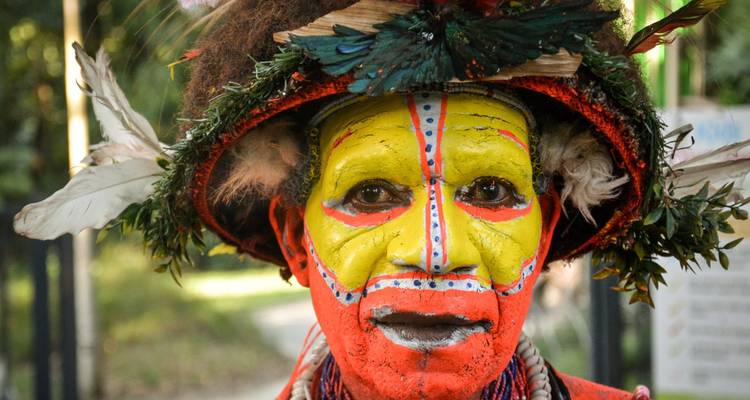 Portrait of a person in traditional Papua New Guinean ceremonial face paint and feathered headdress