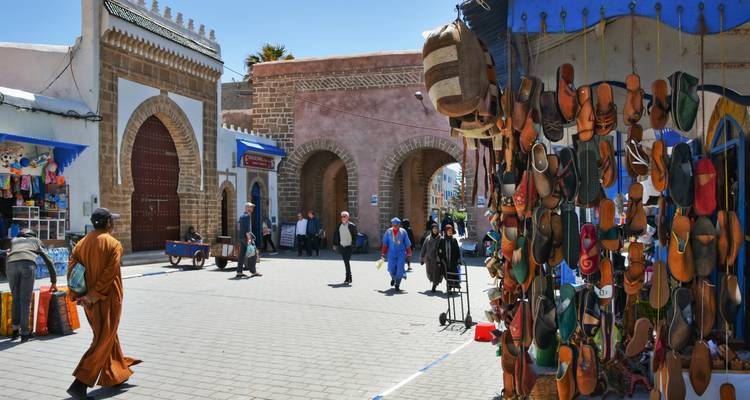 Drukke medina poort met hangende leren goederen en lokale bewoners die lopen