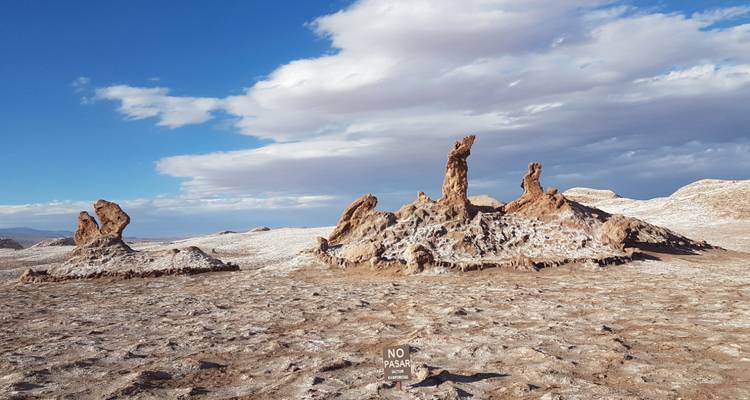 Trockene salzverkrustete Wüstenlandschaft mit ungewöhnlichen Felsformationen unter einem strahlend blauen Himmel.