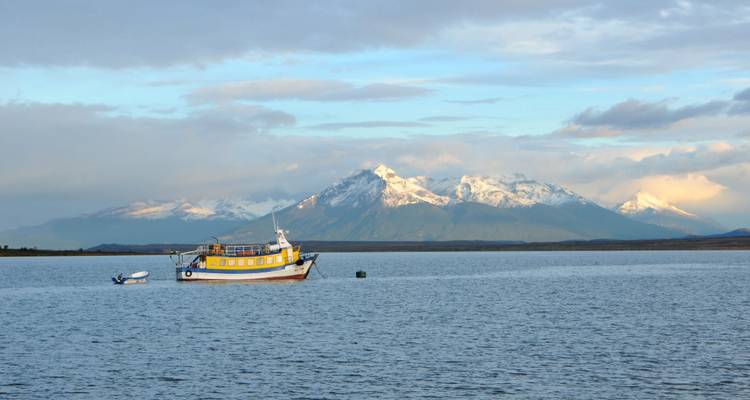 Kleines gelbes Boot, das auf ruhigen patagonischen Gewässern schwimmt, mit schneebedeckten Bergen in der Ferne.