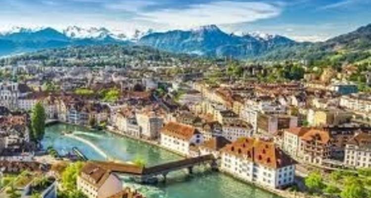 Aerial view of Lucerne’s old town, Chapel Bridge and Reuss River backed by distant Alps.