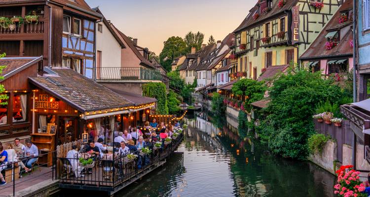 Comensales nocturnos disfrutando de restaurantes junto al canal entre casas con entramado de madera en la Petite France de Estrasburgo