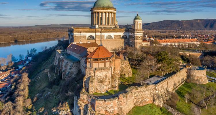 Luftaufnahme einer großartigen Basilika auf einem Hügel mit Blick auf einen Fluss und die umliegende Landschaft unter blauem Himmel.