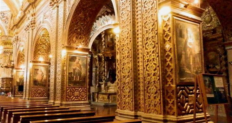 Lavishly decorated church interior with carved columns, gold leaf and framed religious paintings.