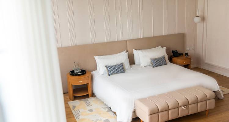 Bright modern hotel room with king-size bed, neutral décor, bedside tables and soft natural light.