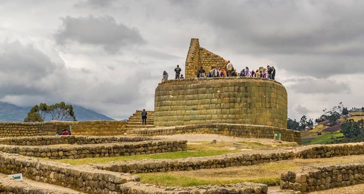 Besucher auf dem runden Sonnentempel der Inka-Ruinen von Ingapirca unter dramatischem Himmel.