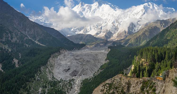 Un pic dramatique couronné de neige s'élève au-dessus d'une vallée sculptée par les glaciers et d'une dense forêt verte dans le nord du Pakistan.