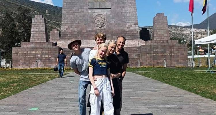 Familie posiert vor dem Mitad del Mundo Denkmal, das den Äquator in der Nähe von Quito markiert.