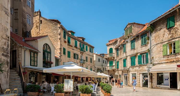 Charmante stenen steeg in de oude stad van Split omzoomd met cafés, groene luiken en terrasgangers