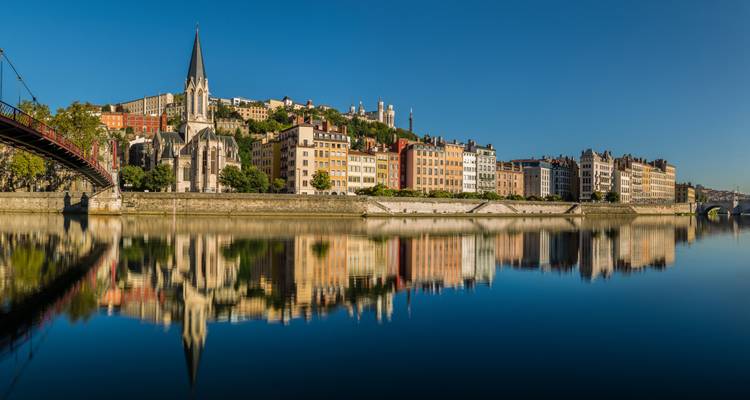 Spiegelstille Saône, die farbenfrohe Gebäude und die Saint-Georges-Kirche mit dem Fourvière-Hügel in Lyon reflektiert.