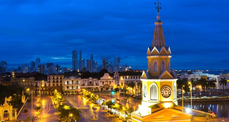 Evening cityscape of Cartagena with illuminated clock tower and colonial streets glowing.