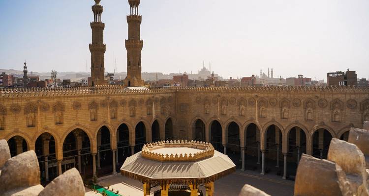 Vista elevada del amplio patio y arcos del histórico complejo de la Mezquita Al Azhar de El Cairo en un día brumoso.