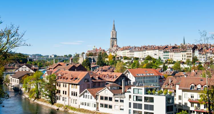 Sunny panorama of Bern’s old town roofs and the towering Bern Minster beside the Aare River.