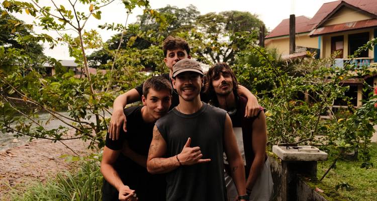 Quatre amis sourient pour un portrait dans un jardin de village rustique au bord de la rivière.