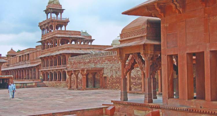 Extenso complejo palaciego de arenisca roja de Fatehpur Sikri con un visitante solitario caminando por el patio.