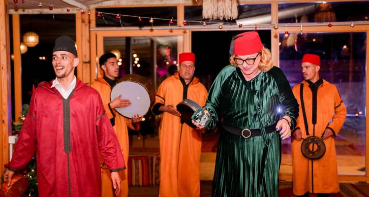 Traditionelle marokkanische Musiker und ein Gast tanzen in einem dekorierten Saal