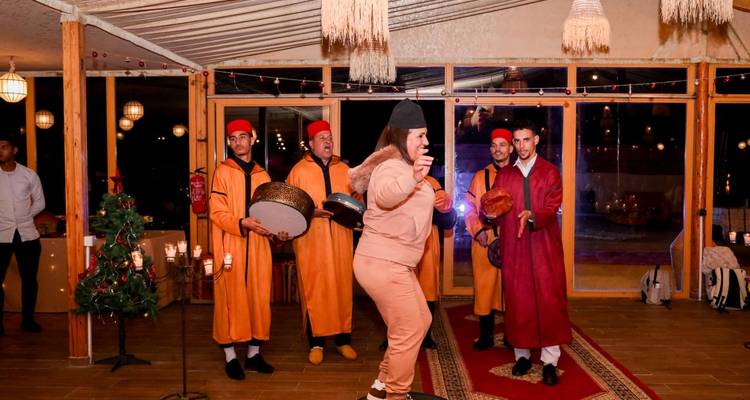 Gäste und Musiker, die traditionellen Tanz in einem beleuchteten Restaurantsaal aufführen