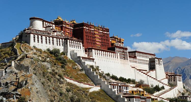 Majestueux Palais du Potala perché sur une colline avec un ciel bleu clair et des escaliers menant vers le haut.